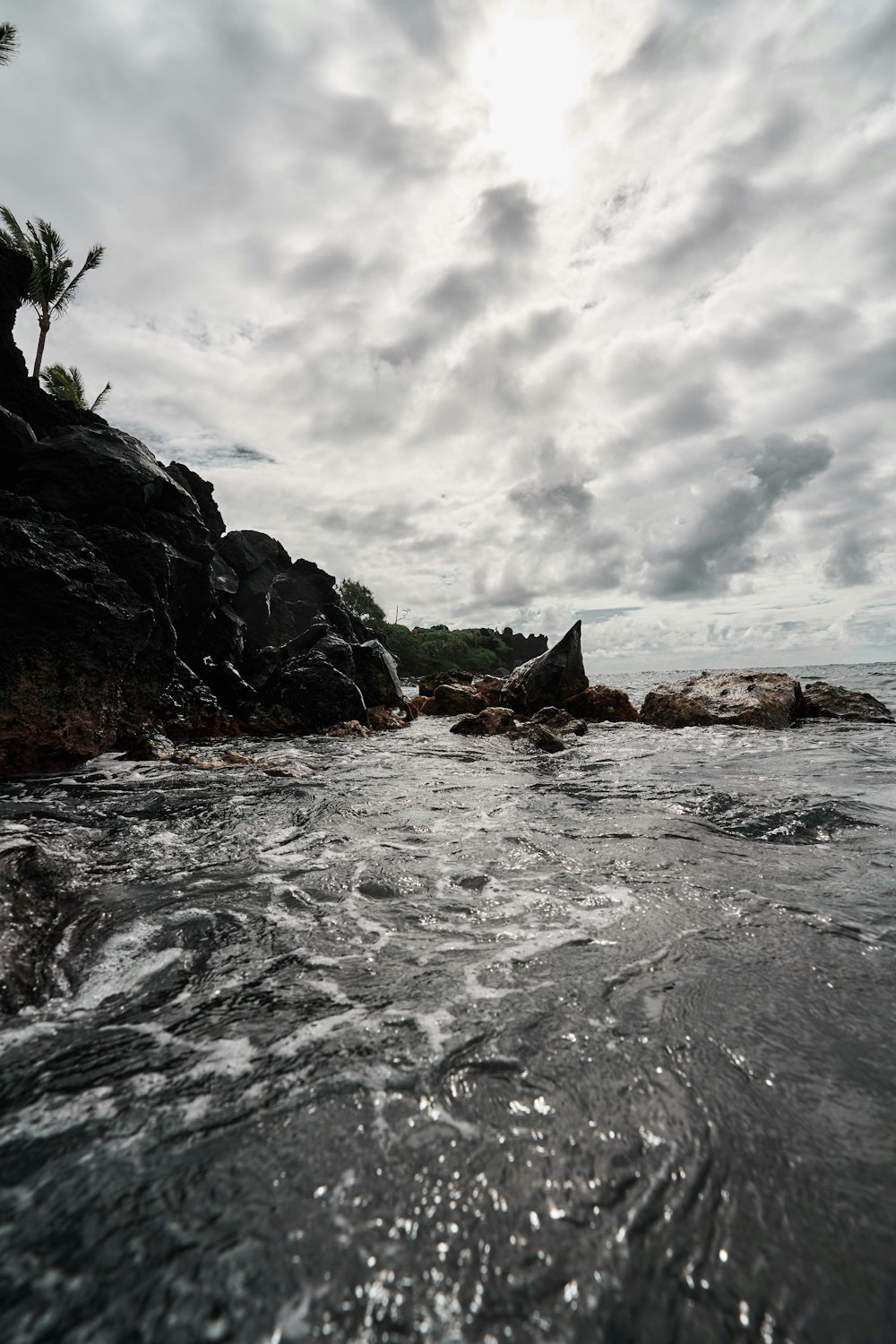 a body of water surrounded by rocks under a cloudy sky