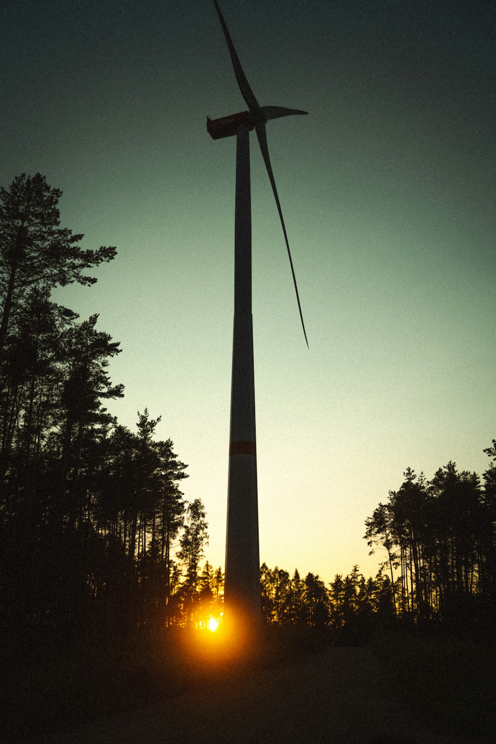 the sun is setting behind a wind turbine