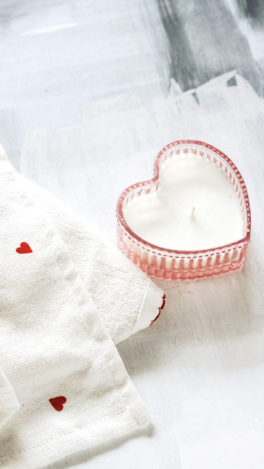 a heart shaped candle sitting next to a napkin