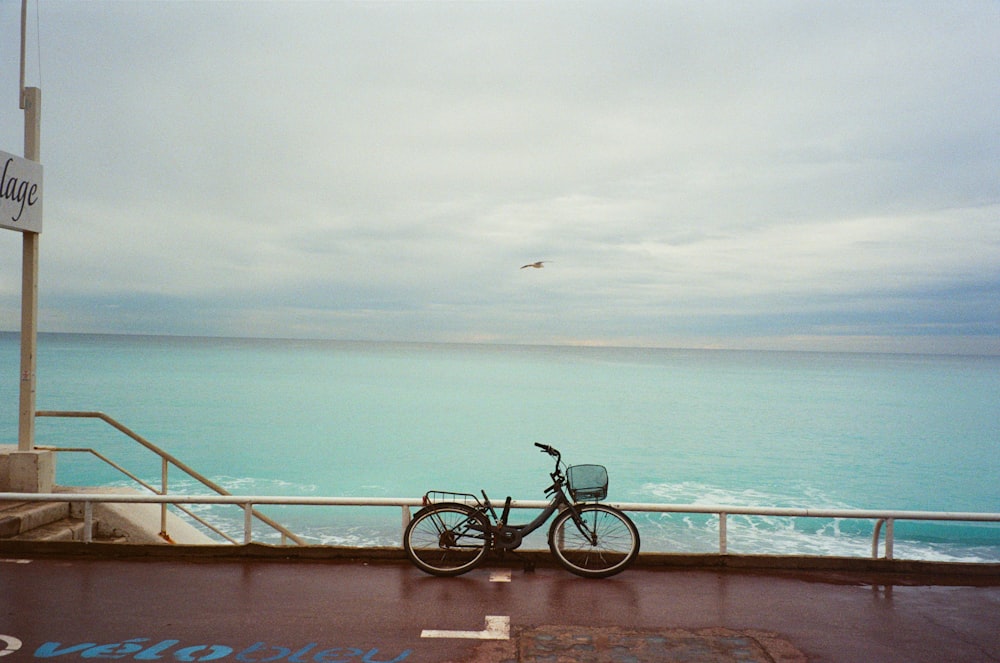 a bicycle parked on a railing near the ocean