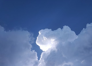 a plane flying through a cloudy blue sky