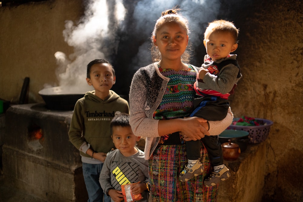 a woman holding a child in front of a group of children