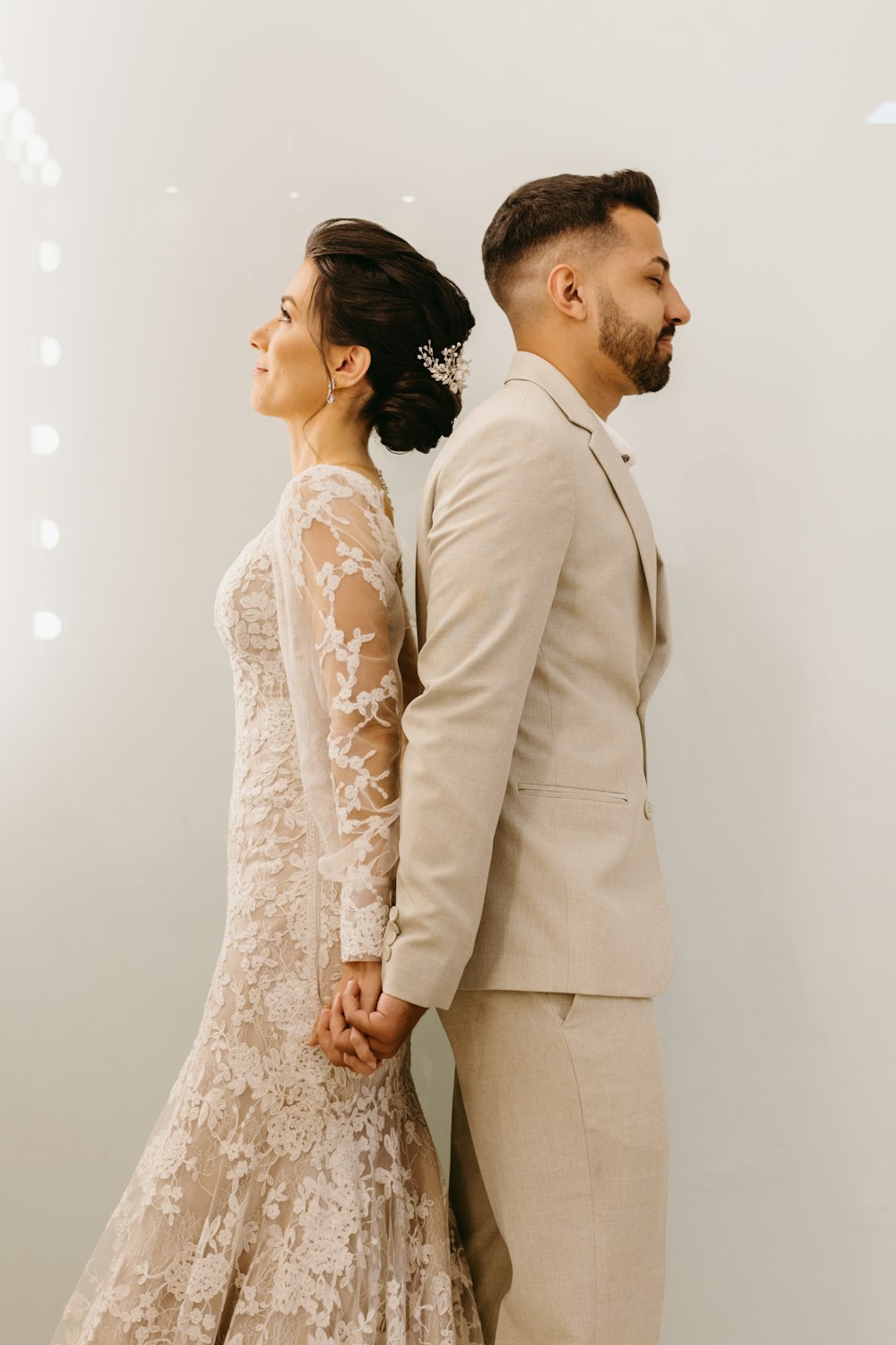 a man and a woman holding hands in front of a white wall