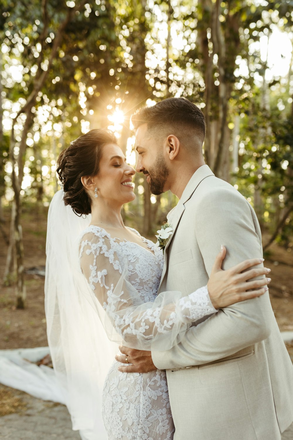 a bride and groom embracing in front of the sun