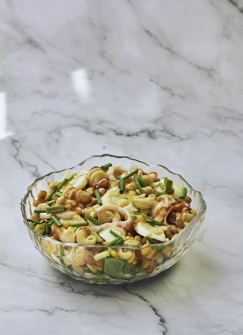 a glass bowl filled with pasta and vegetables