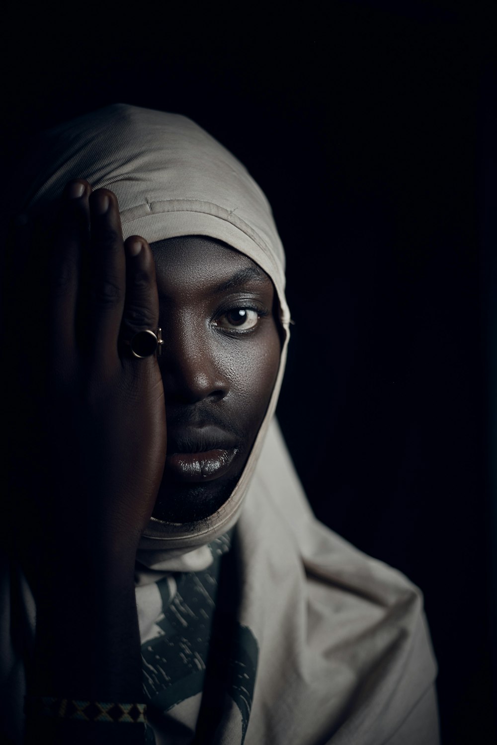 a woman in a headscarf holding her hands to her face