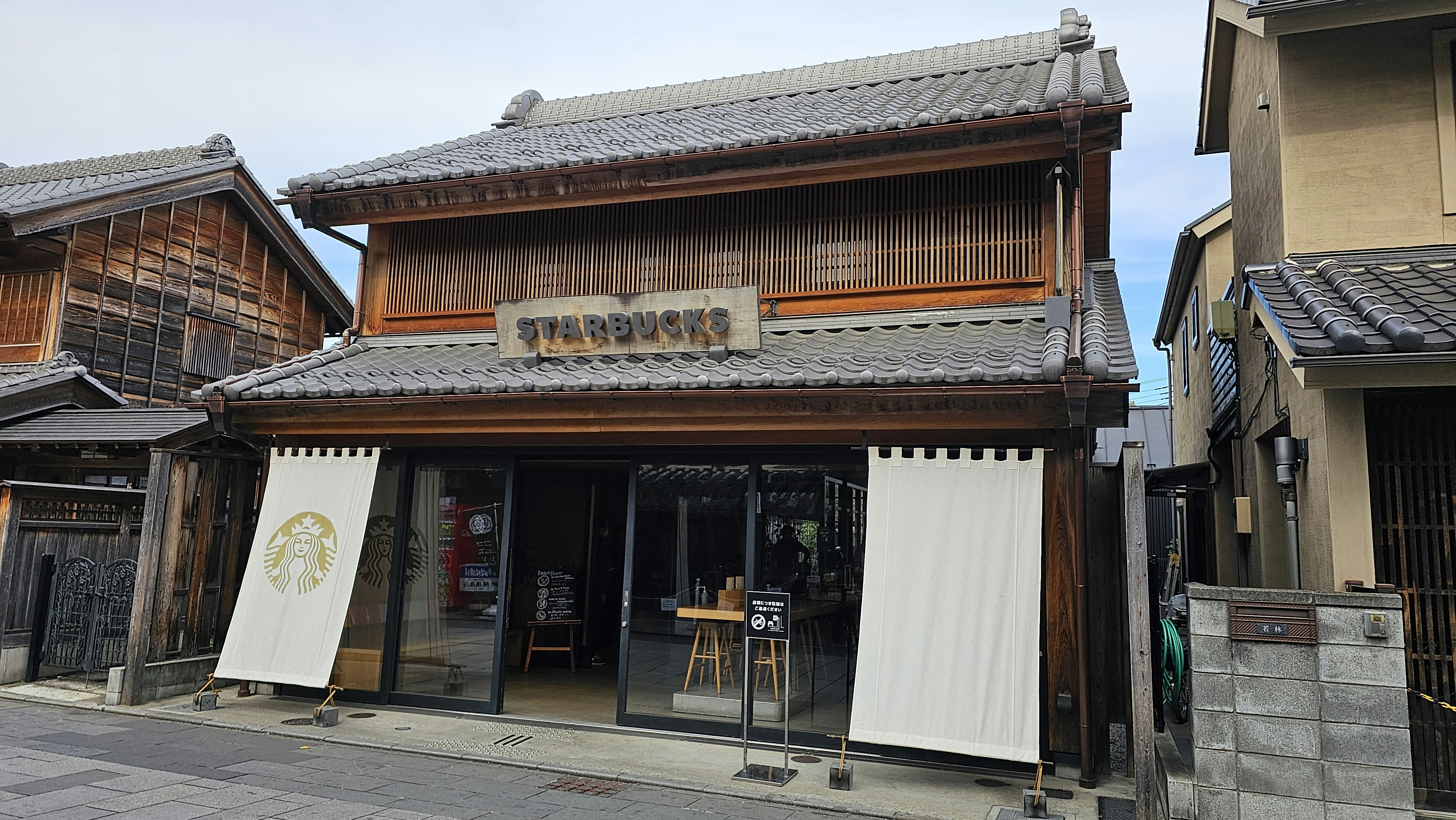 Interior of a bustling Japanese cafe chain like Starbucks or Doutor, with people working on laptops