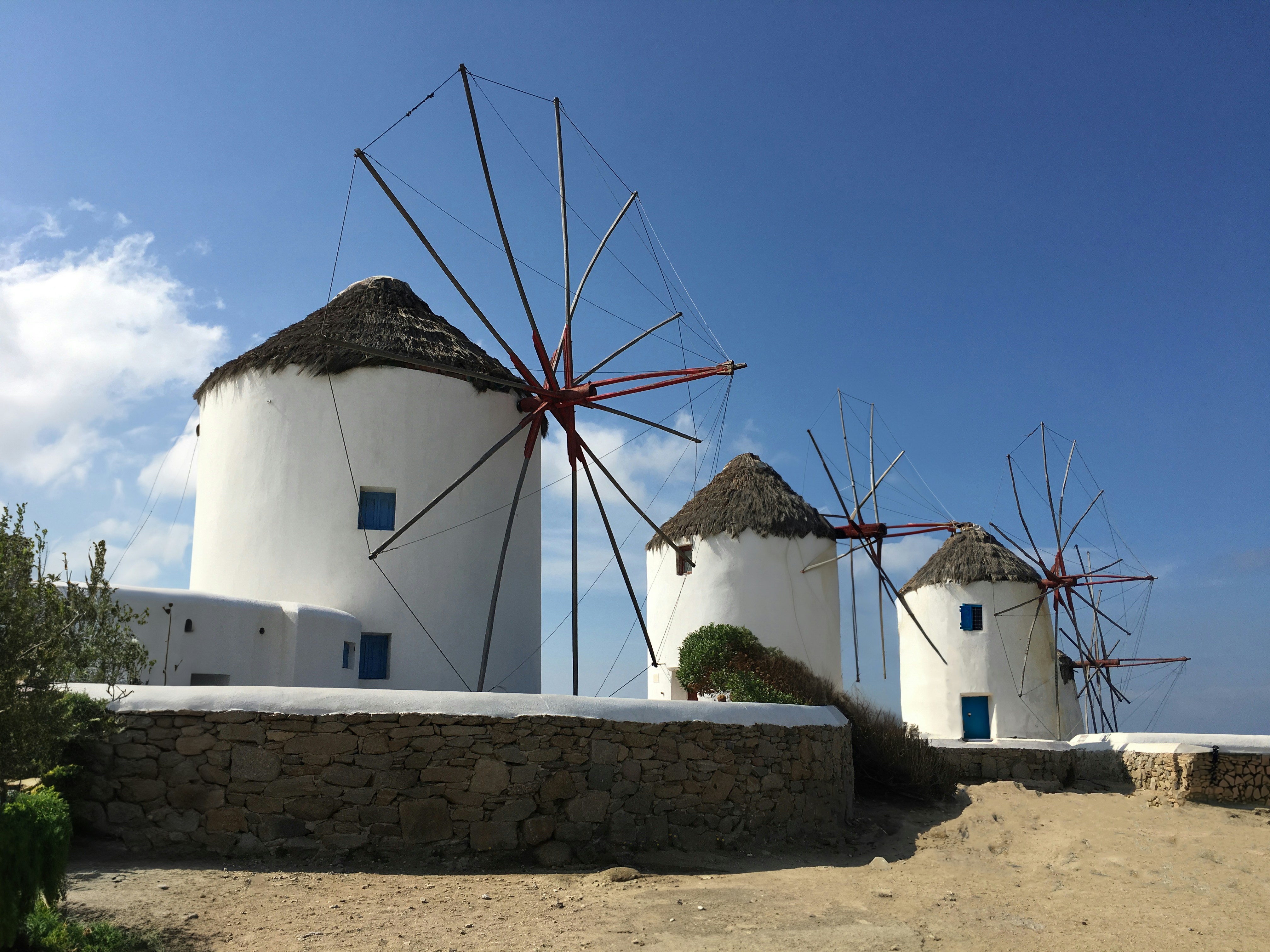 a row of white windmills next to a stone wall
