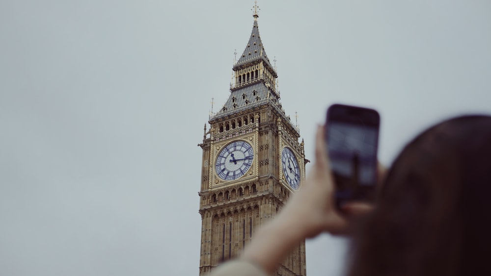 Uma pessoa tirando uma foto da torre do relógio Big Ben