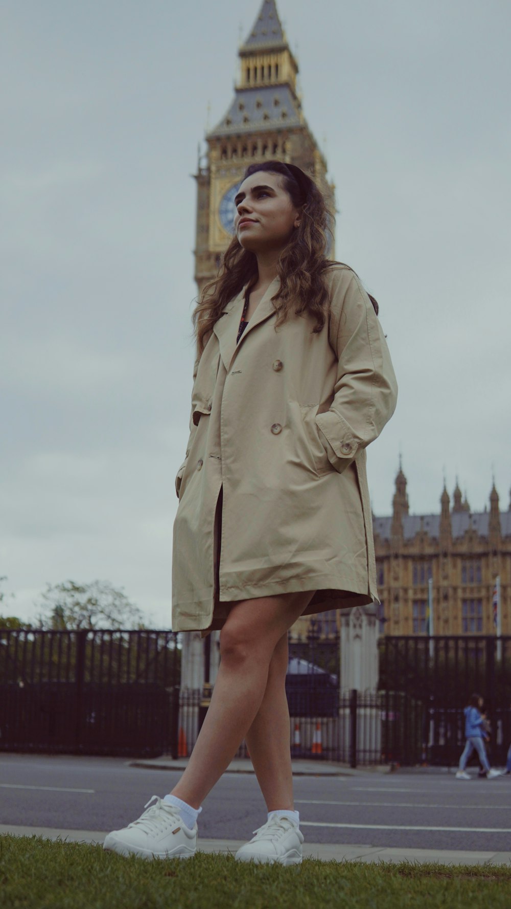 une femme debout devant une tour de l’horloge