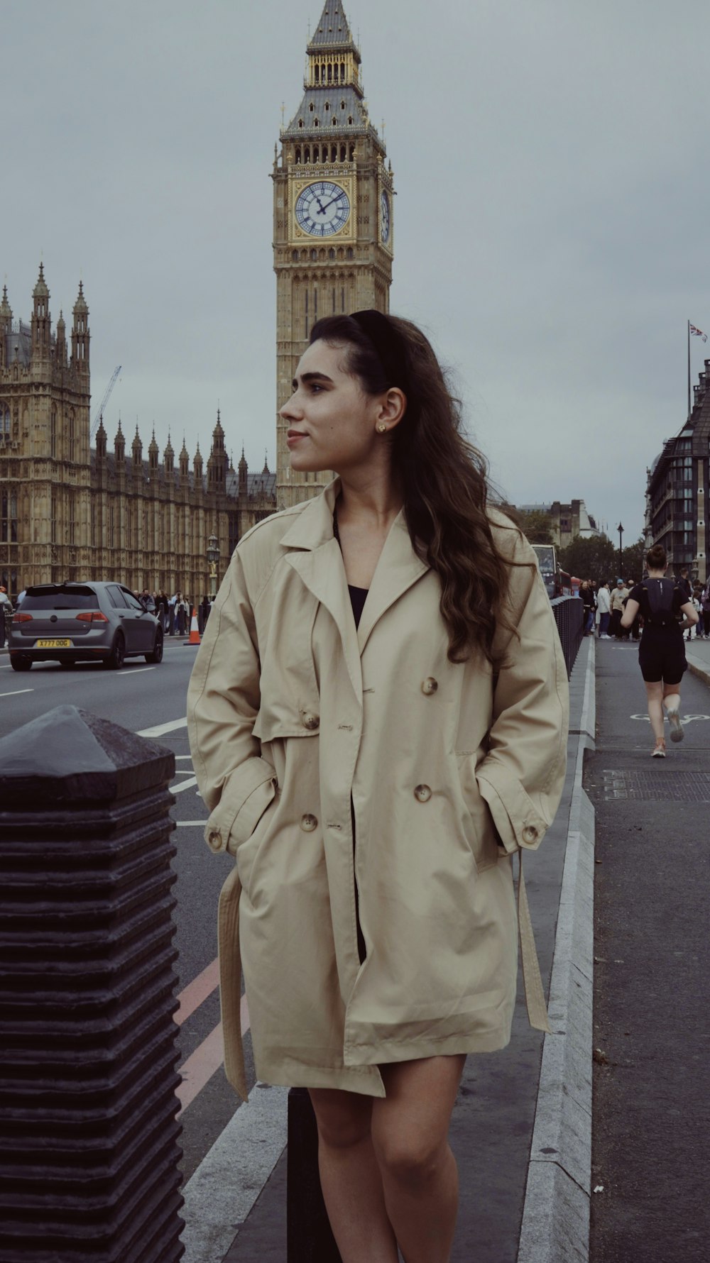 a woman in a trench coat standing on a sidewalk