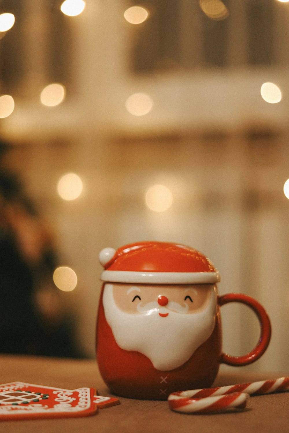 a santa clause mug sitting on a table next to a candy cane