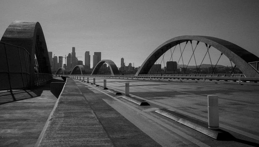 a black and white photo of a bridge with a city in the background