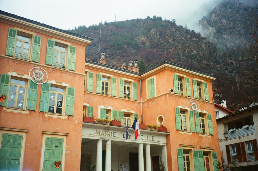 a large orange building with green shutters on the front