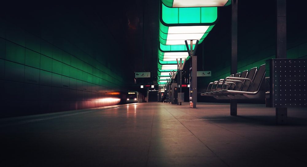 a train station with benches and lights at night
