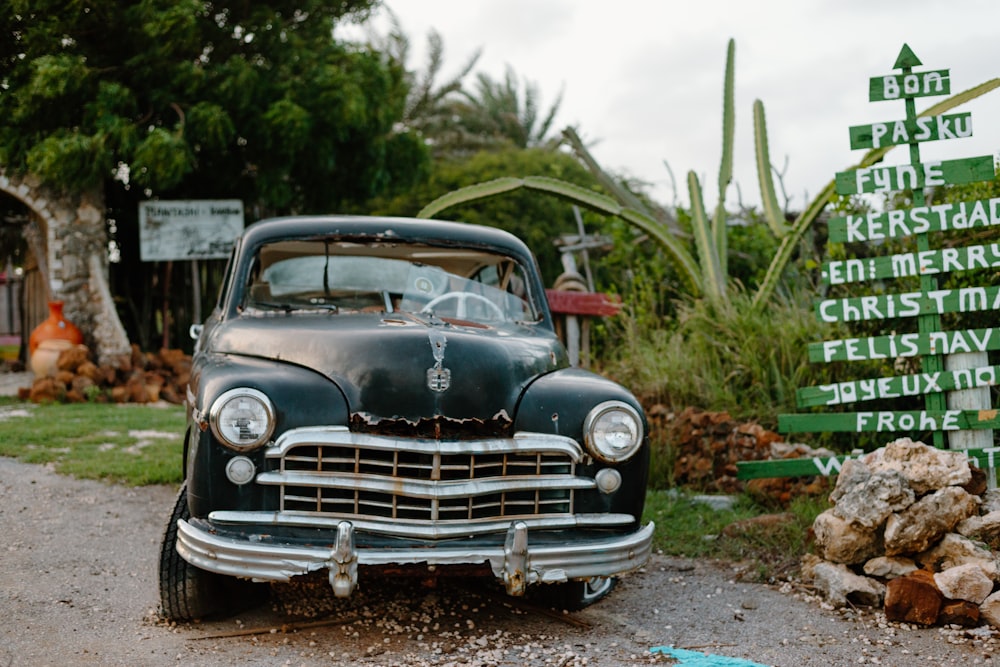 an old car is parked in front of a sign