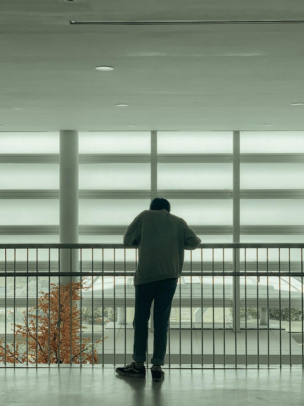 a man standing in front of a window next to a fence