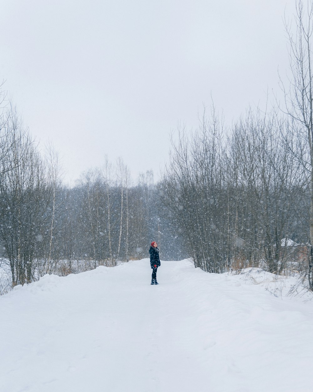 a person standing in the middle of a snow covered road