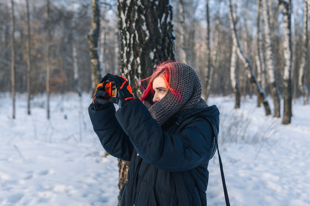 a woman standing in the snow holding a pair of skis