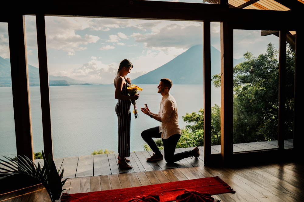 a man kneeling down next to a woman holding flowers