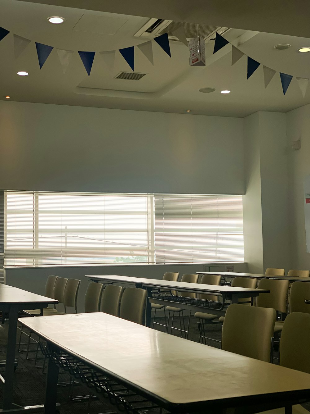 a classroom with tables, chairs, and a projector screen