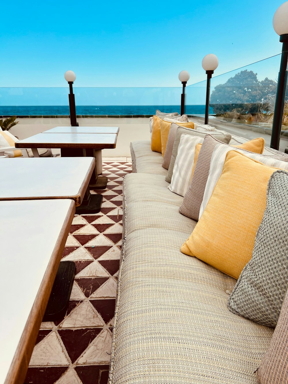 a couch and tables on a patio overlooking the ocean