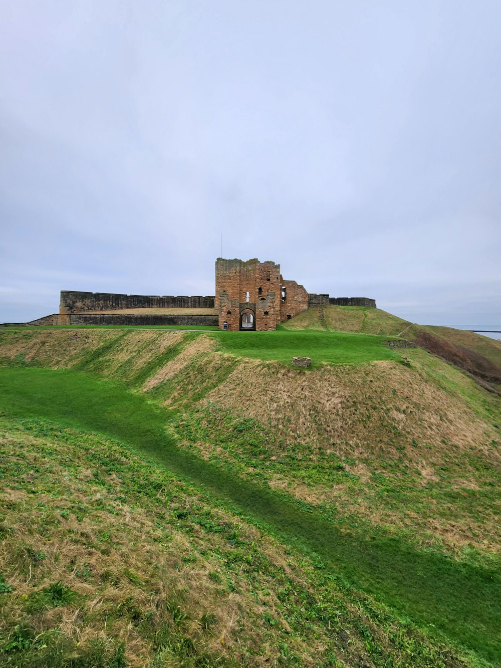 an old building sitting on top of a green hill