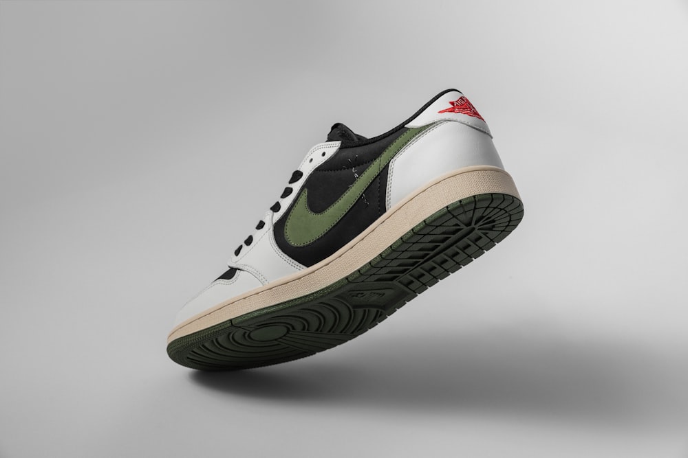 a pair of white and green sneakers on a gray background