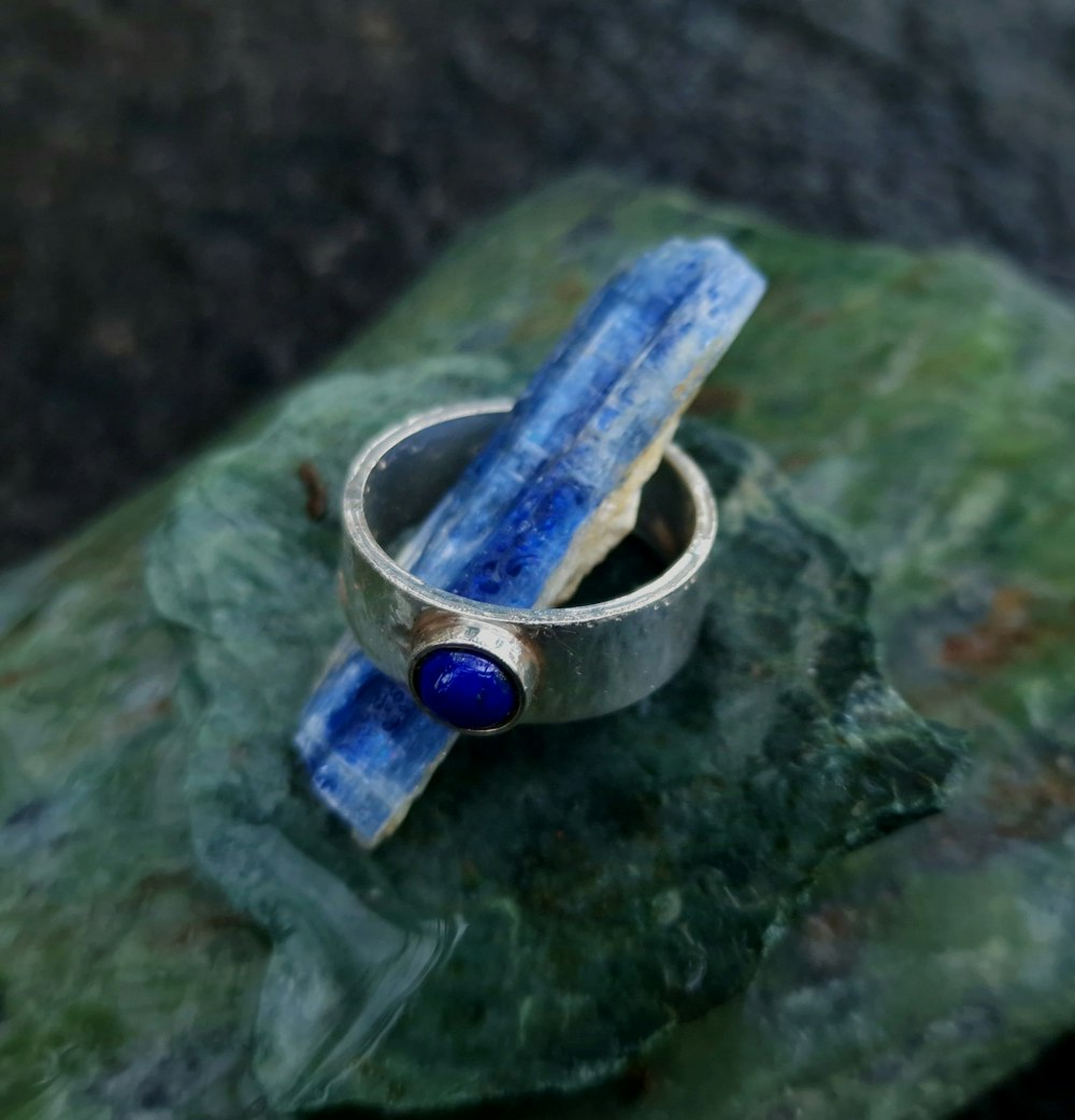 um anel de prata com uma pedra azul em cima dele