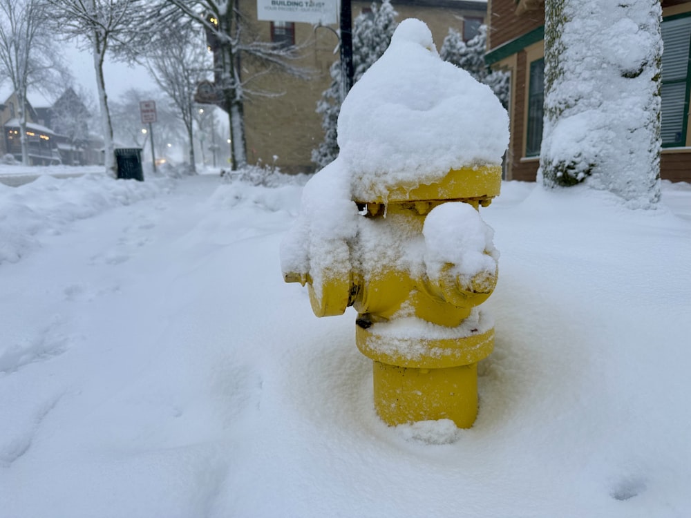 a yellow fire hydrant is covered in snow