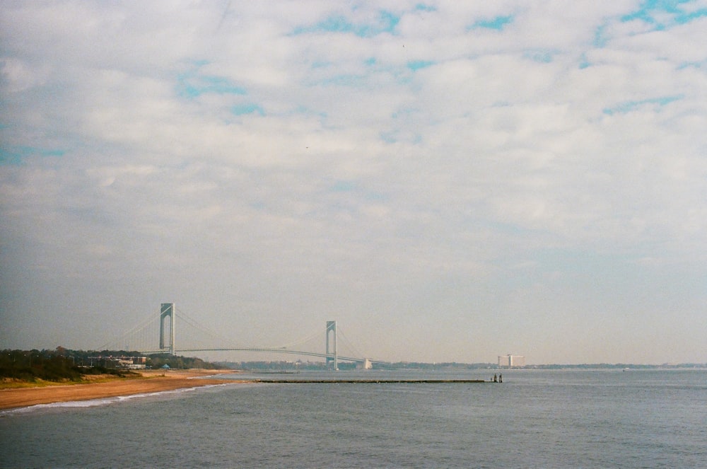 a large body of water with a bridge in the background