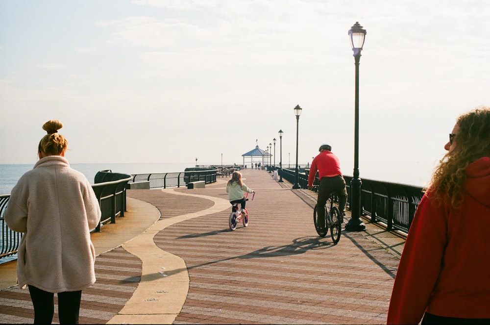 a group of people walking along a pier next to the ocean