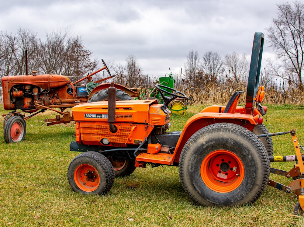 an orange tractor sitting on top of a lush green field