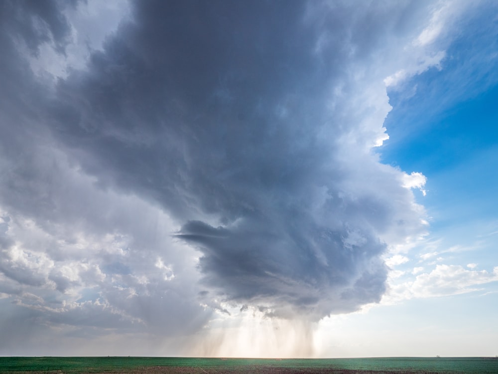a large storm cloud looms over a field