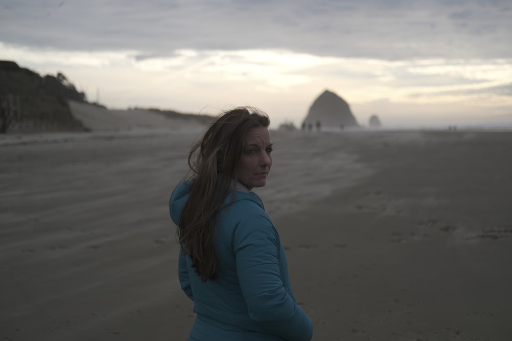 a woman standing on top of a sandy beach