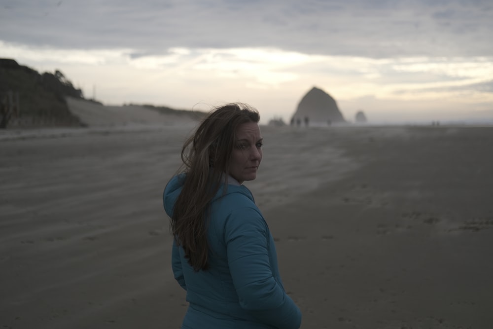 una donna in piedi in cima a una spiaggia sabbiosa