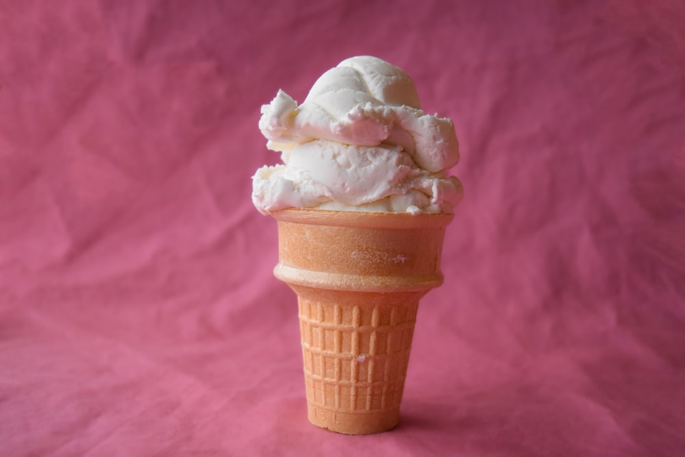 a cone of ice cream on a pink background
