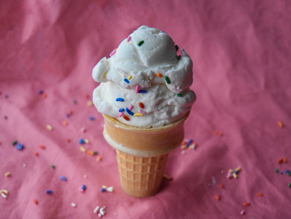 a scoop of ice cream with sprinkles on a pink background