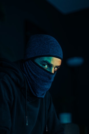 a man wearing a black hoodie and a blue mask
