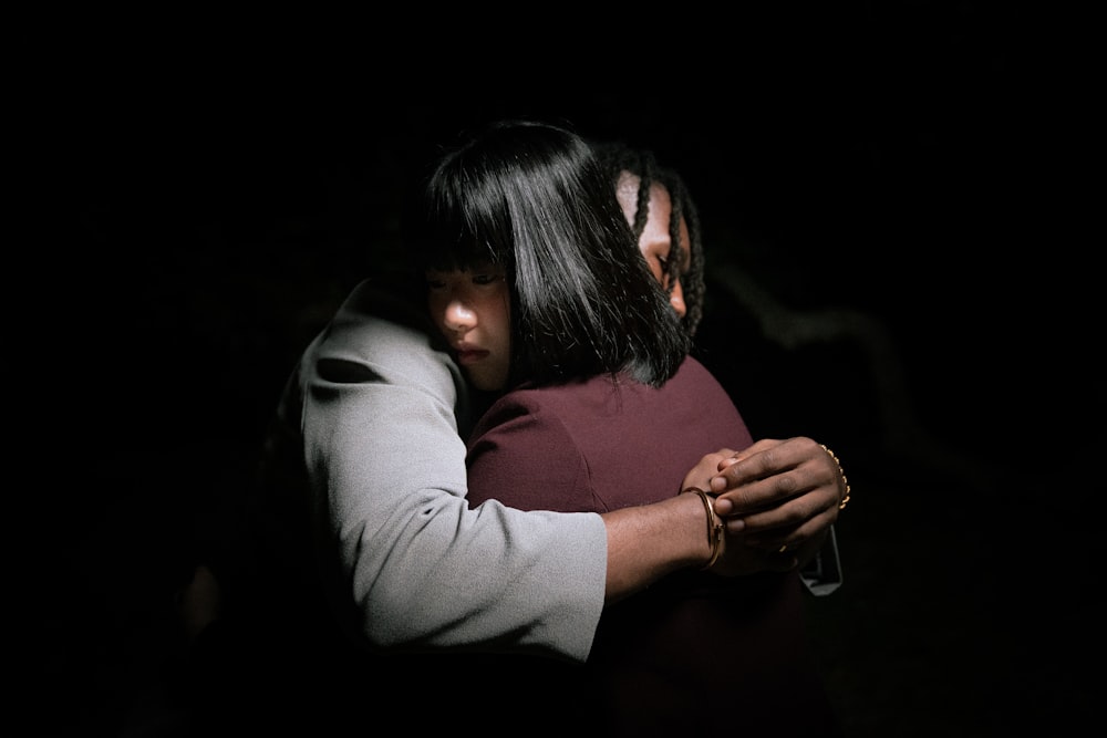 a woman hugging another woman in the dark