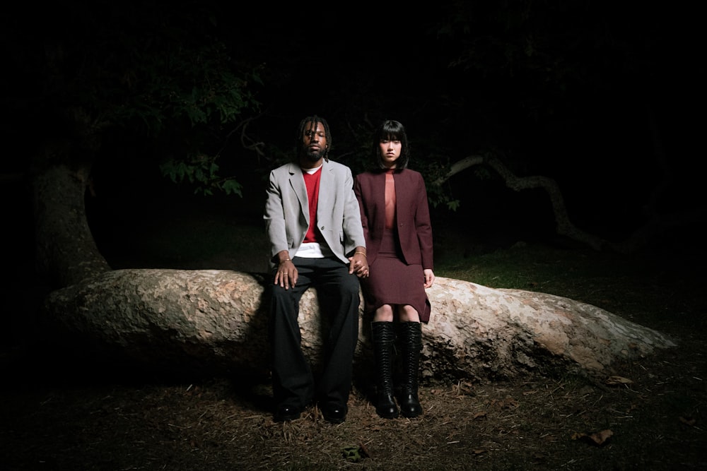 a man and a woman sitting on a log in the dark