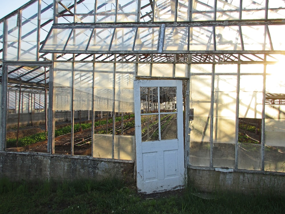 an old greenhouse with a white door and windows