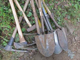a pile of shovels and forks laying on the ground
