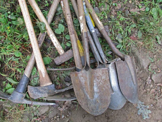 a pile of shovels and forks laying on the ground