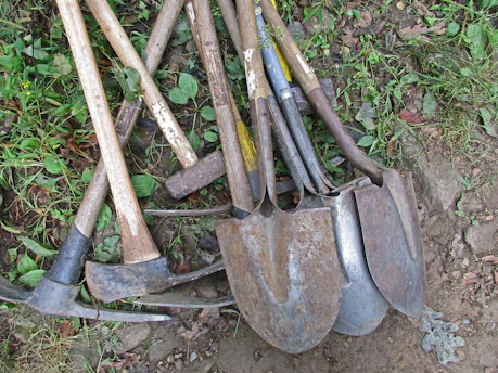 a pile of shovels and forks laying on the ground