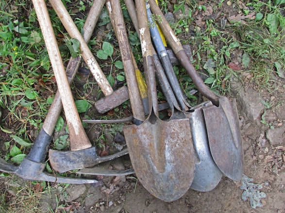 a pile of shovels and forks laying on the ground