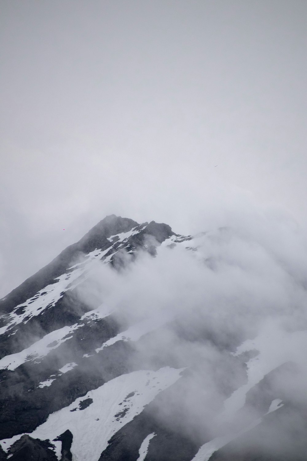 a mountain covered in snow and clouds on a cloudy day