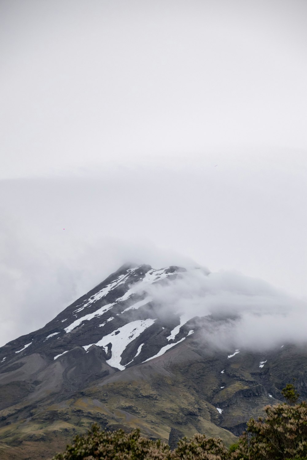 a mountain covered in snow and clouds on a cloudy day