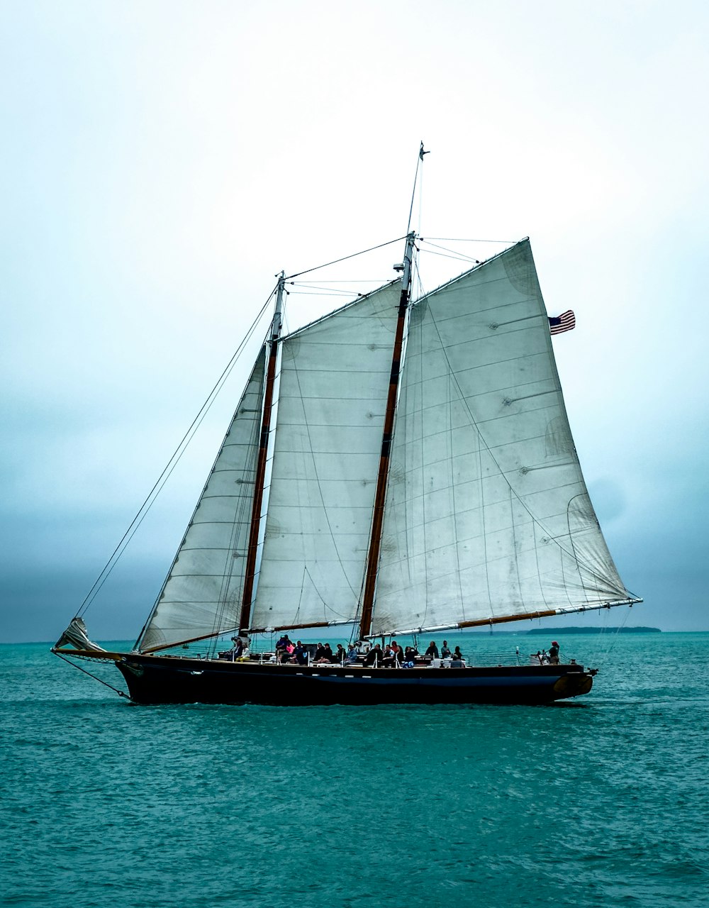 a sailboat with white sails on a body of water