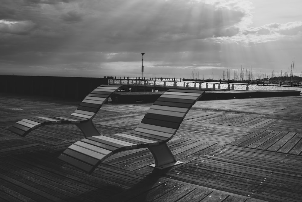a black and white photo of a bench on a pier